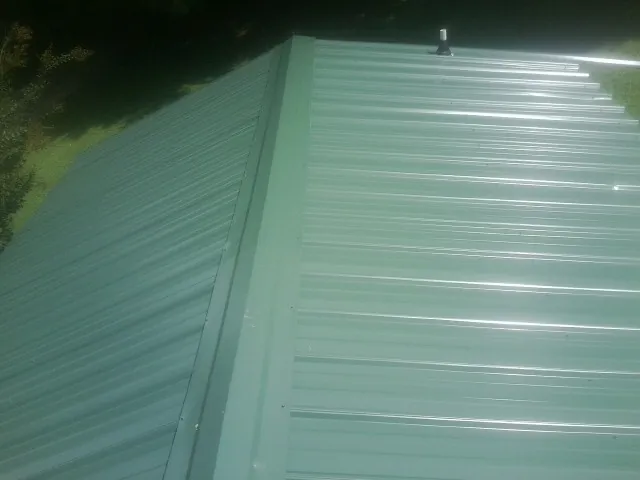 New green metal panels meeting at the ridge of a roof — Flat Roof Repair work by our crew in Winthrop