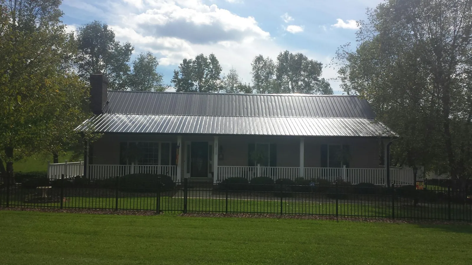 Gray metal roof on a brick ranch with a full width front porch — Gutter Guard Installation work by our crew in Winthrop